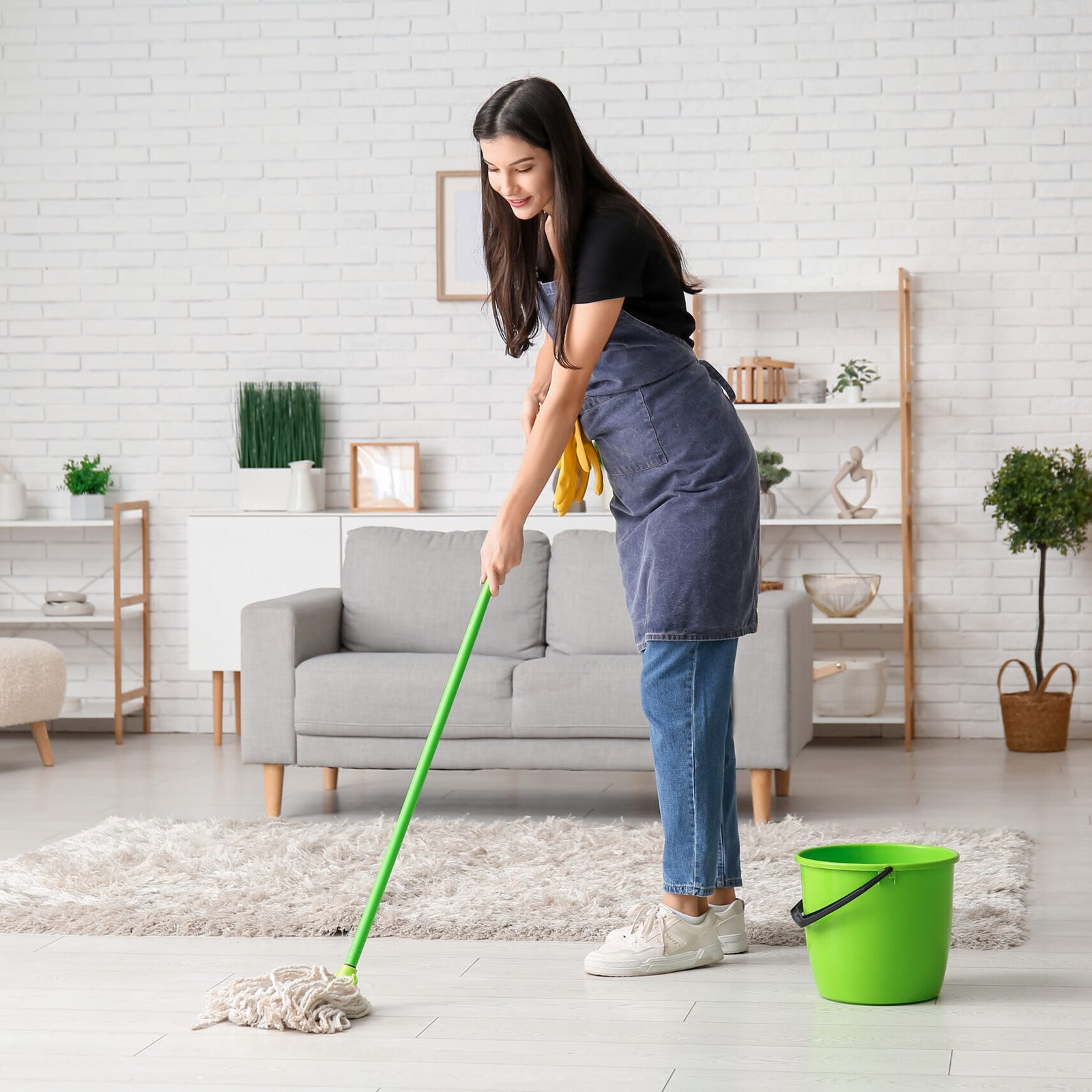 Young woman mopping floor in living room